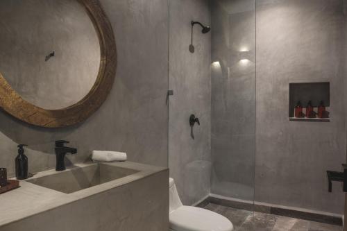 a bathroom with a shower and a toilet and a mirror at Urbano by Sundara in Tulum