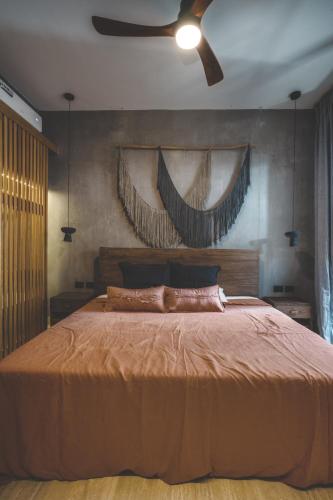 a bedroom with a large bed with a ceiling fan at Urbano by Sundara in Tulum