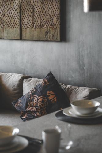 a pillow on a couch with a table with plates at Urbano by Sundara in Tulum