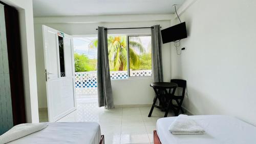 a room with two beds and a window and a table at Keylee's Lodging in San Andrés