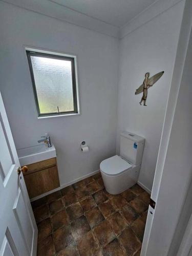 a small bathroom with a toilet and a window at Whangamata Harbour Haven in Whangamata