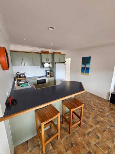 a kitchen with a black counter and two stools at Whangamata Harbour Haven in Whangamata