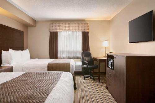 a hotel room with two beds and a flat screen tv at Days Inn by Wyndham Leamington in Leamington