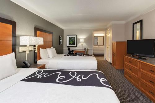 a hotel room with two beds and a flat screen tv at Days Inn by Wyndham Gainesville Florida in Gainesville