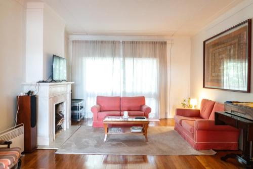 un soggiorno con un divano rosso e un tavolo di Spacious, Luxurious, and Charming Apartment in Premium Porto Location with PARKING a Porto