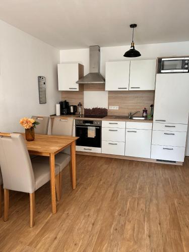 a kitchen with white cabinets and a wooden table at PrimeBnb Am Marktplatz in Bad Hersfeld