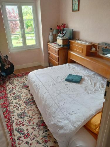 - une chambre avec un lit, une commode et une guitare dans l'établissement Via Lactéa, à Saint-Goussaud