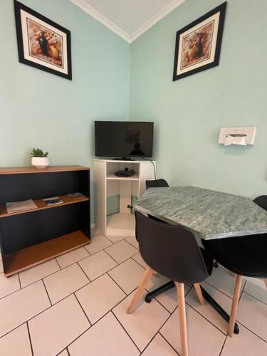 a room with a table and chairs and a television at The Tree Motel in Narooma