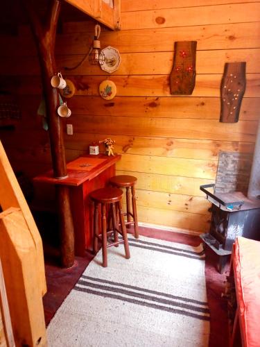 a room with a table and stools in a cabin at Tiny houses temáticas en medio del bosque el jardín del chucao in Maullín