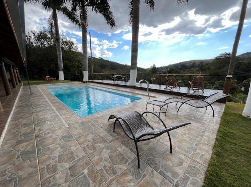a swimming pool with two benches next to at Chácara Pimenta Vermelha in Socorro