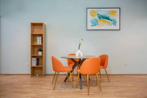 a dining room with a table with orange chairs at Acogedor departamento en Roma in Mexico City