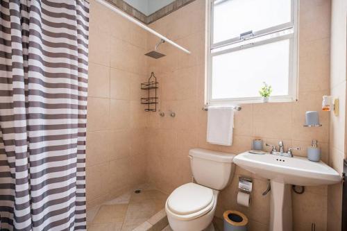 a bathroom with a toilet and a sink and a window at Acogedor departamento en Roma in Mexico City