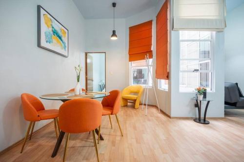 a dining room with a glass table and orange chairs at Acogedor departamento en Roma in Mexico City