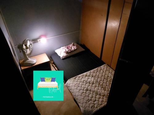 a small room with a bed and a table with a lamp at HostelBed and Retreat Phitsanulok in Phitsanulok