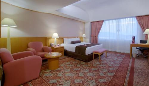 a hotel room with a bed and two chairs at Crowne Plaza Hotel Mexico City North-Tlalnepantla by IHG in Mexico City