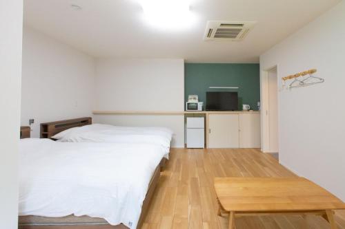 a bedroom with a white bed and a wooden table at ホテル森のしずく in Shimoda