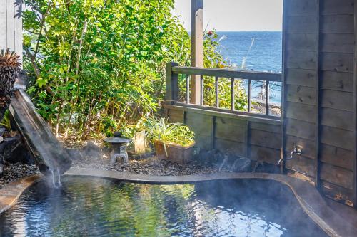 a water fountain in front of a house with the ocean at Izu atagawa Yubana mankai -Adult Only- in Higashiizu
