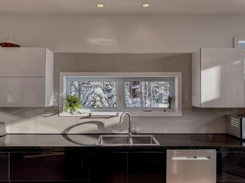 a kitchen with a sink and two windows at Le Willow Exitchalets Lake, Billard & Spa in Val-David
