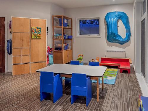 a playroom with a table and blue chairs and a table at Le Willow Exitchalets Lake, Billard & Spa in Val-David