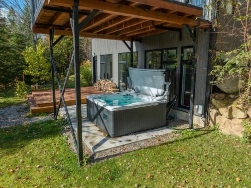 a hot tub under a pergola on a patio at Le Willow Exitchalets Lake, Billard & Spa in Val-David