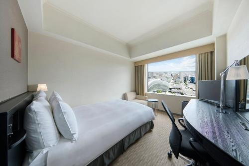 a hotel room with a bed and a desk and a window at ANA Crowne Plaza Kanazawa by IHG in Kanazawa