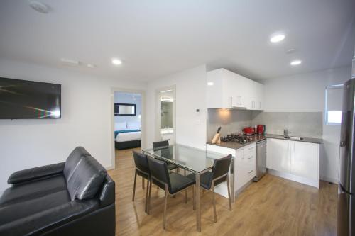 a kitchen and living room with a glass table and a couch at Jesmond Executive Villas in Newcastle