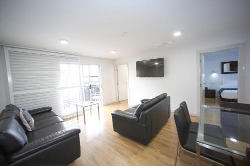 a living room with black leather furniture and a bed at Jesmond Executive Villas in Newcastle