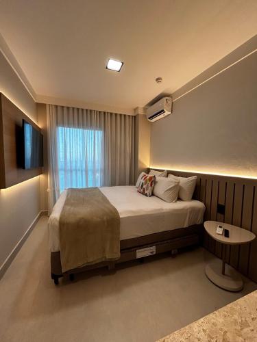 a bedroom with a large bed and a table at Flat Praia do Canto 2Q-2B Long Stay TRIÂNGULO DAS BERMUDAS in Vitória
