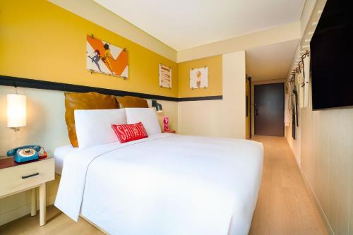 a bedroom with a large white bed and yellow walls at Moxy Seoul Myeongdong in Seoul
