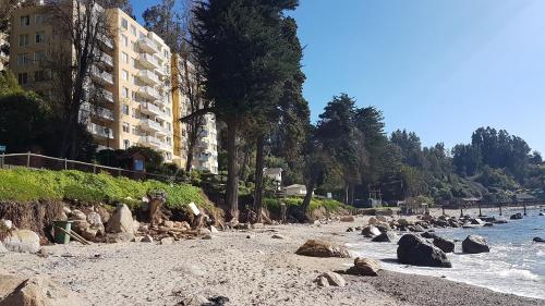 a beach with rocks and a building and the water at Departamento Bahía Pelícanos, Horcón in Puchuncaví
