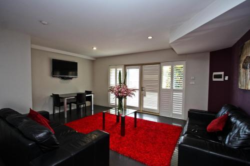 a living room with a black couch and a red rug at Jesmond Executive Villas in Newcastle