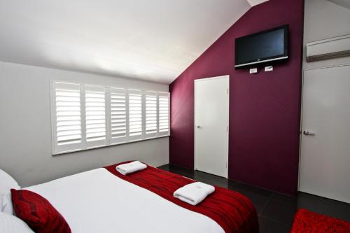 a bedroom with a bed with a red wall at Jesmond Executive Villas in Newcastle