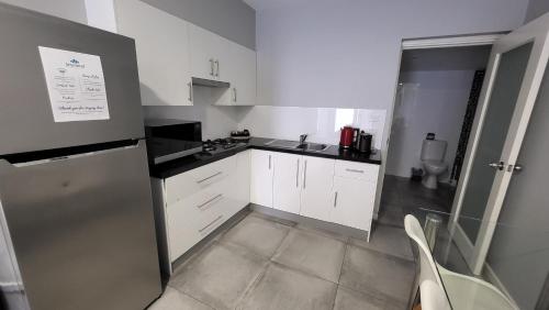 a small kitchen with white cabinets and a silver refrigerator at Jesmond Executive Villas in Newcastle
