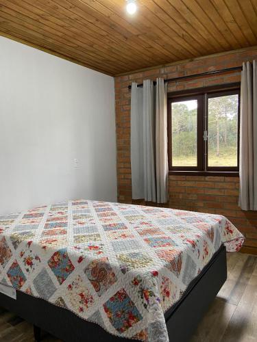 a bedroom with a bed with a quilt on it at Refúgio Rota das Nuvens in Bom Jardim da Serra