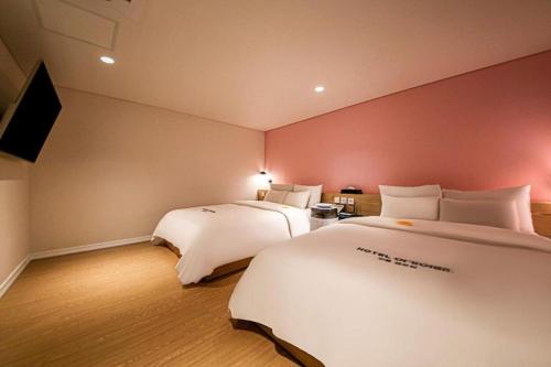 a hotel room with two beds and a flat screen tv at Hotel Yeogiuhtte Gangneung Gyeongpo in Gangneung
