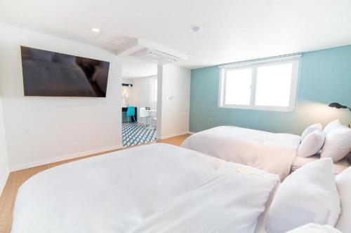 a white bedroom with two beds and a window at Hotel Yeogiuhtte Gangneung Gyeongpo in Gangneung