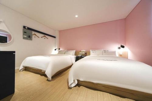 two beds in a room with pink walls at Hotel Yeogiuhtte Gangneung Gyeongpo in Gangneung