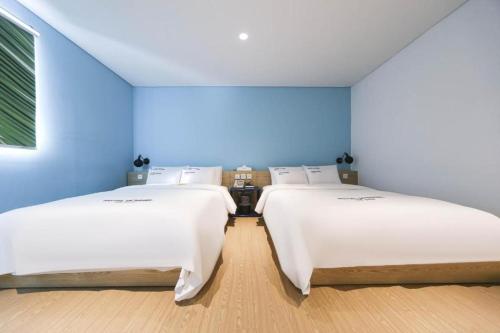 two beds in a room with a blue wall at Hotel Yeogiuhtte Gangneung Gyeongpo in Gangneung