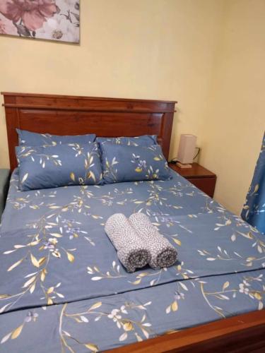 a bed with a blue comforter with a hat on it at Zhabret's Place II in Lapu Lapu City