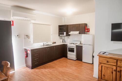 a kitchen with white appliances and brown cabinets at The Sundowner Cabin & Tourist Park in Whyalla