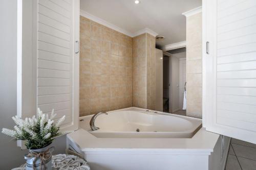 a white bath tub in a bathroom with tiles at Rolling Surf Resort in Caloundra