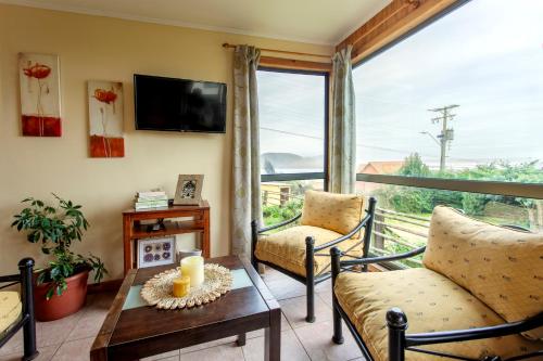 a living room with a balcony with a tv and chairs at Cabañas Piedra Grande in Pichilemu