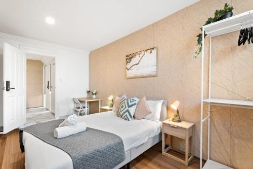 a bedroom with a white bed and a staircase at Boutique Queen Room - Centrally Located at Glenfield - Shared Bathroom in Glenfield