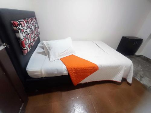 a bed with an orange and white blanket on it at Apartamentos CasaMJ Tunja Confort y Parqueadero in Tunja