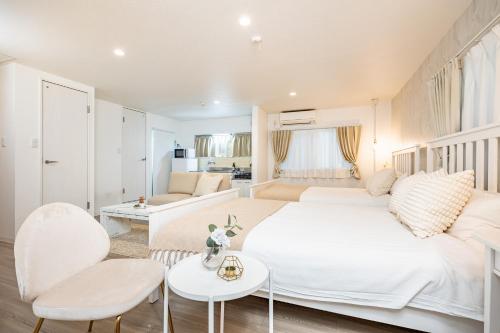 a white bedroom with a white bed and a living room at Bijou Suites Granpia in Osaka