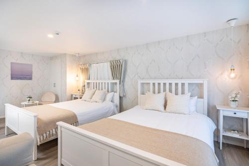 two beds in a bedroom with white walls at Bijou Suites Granpia in Osaka