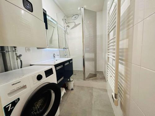La salle de bains blanche est pourvue d'un lave-linge et d'une douche. dans l'établissement Appartement 2 pièces cabine avec jardin, proche centre et marché - 4 couchages, Le Pouliguen - FR-1-245-208, au Pouliguen