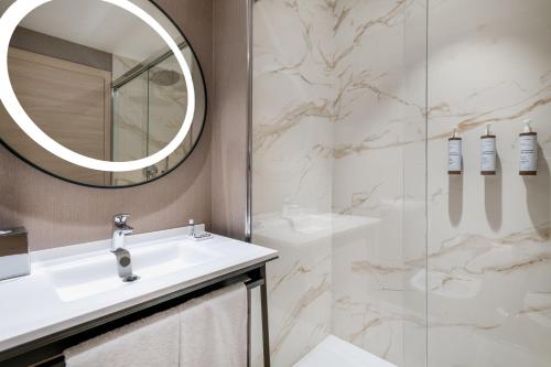 a bathroom with a sink and a mirror and a shower at AC Hotel by Marriott Clodio Roma in Rome