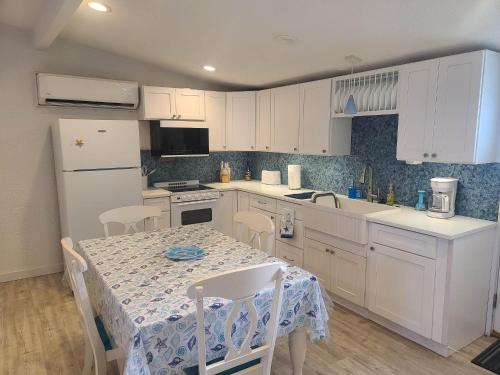 a kitchen with white cabinets and a table with chairs at Coastal Cottage Bay House in Palacios