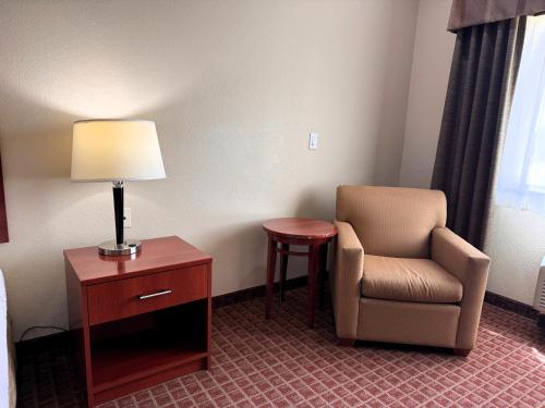 a room with a chair and a lamp and a table at Ramada by Wyndham College Station in College Station